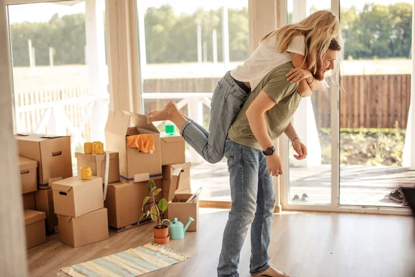 Casal desfrutando em seu novo apartamento, se divertindo enquanto mulher piggyback no homem — Fotografia de Stock