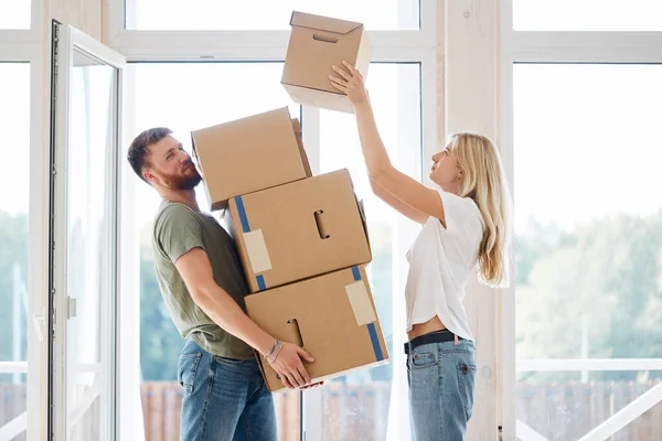 female placing moving boxes on large stack man is holding all
