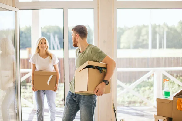 Счастливая пара носит картонные коробки в новый дом в день переезда — стоковое фото