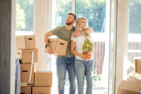 Pareja feliz llevando cajas de cartón en un nuevo hogar en el día de mudanza — Foto de Stock