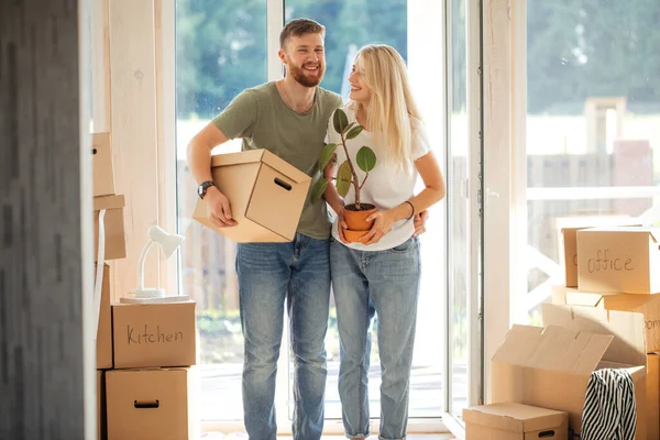 Pareja feliz llevando cajas de cartón en un nuevo hogar en el día de mudanza — Foto de Stock