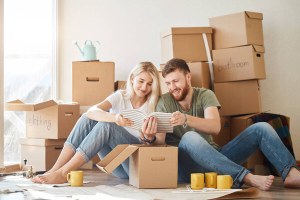 couple with book sitting on bed while moving into new home