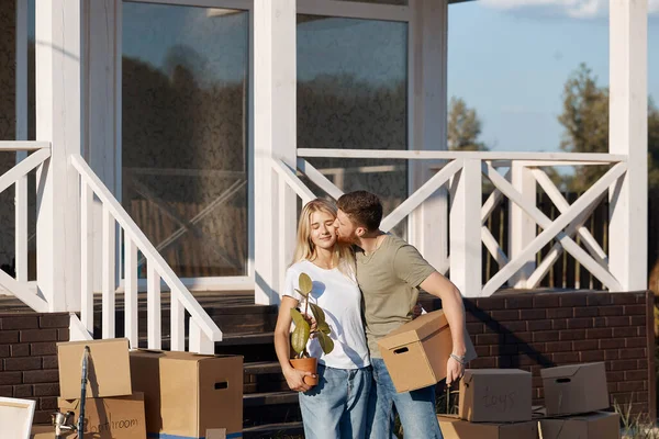 Esposo y esposa de pie frente a la nueva casa de compra con cajas — Foto de Stock