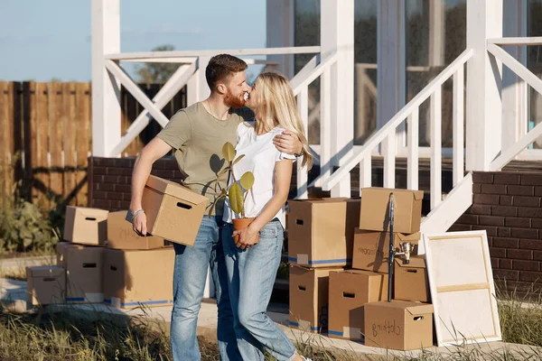 Esposo y esposa de pie frente a la nueva casa de compra con cajas — Foto de Stock