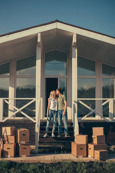 Esposo y esposa de pie frente a la nueva casa de compra con cajas —  Fotos de Stock