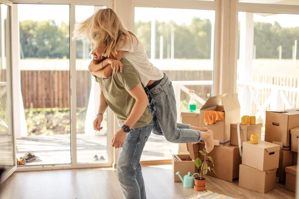 Couple profiter dans leur nouvel appartement, avoir du plaisir tandis que la femme piggyback sur l'homme — Photo