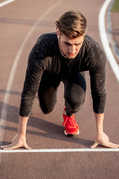 Athlete on starting position at running track. Runner practicing run in stadium racetrack — Stock Photo, Image