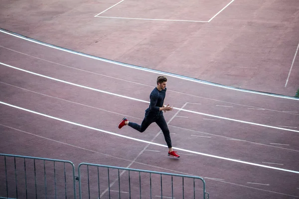 Vista superior Atleta corriendo en pista de atletismo. Corredor corriendo en pista roja en el estadio —  Fotos de Stock