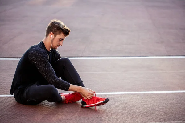 Löpare gör sig redo jogging binda löparskor snören medan du sitter på spår — Stockfoto