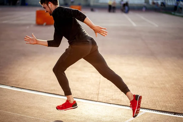 Male athlete wearing black sportwear running at track, side view — Stock Photo, Image