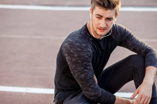 Es hora de descansar. hombre descansando después de correr en pista en el estadio —  Fotos de Stock