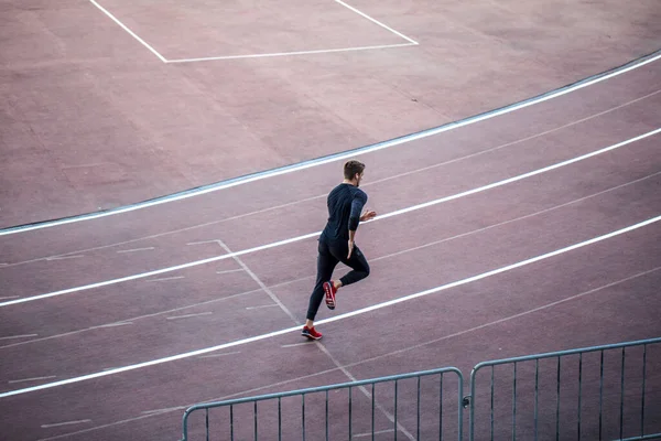 Vista superior Atleta corriendo en pista de atletismo. Corredor corriendo en pista roja en el estadio —  Fotos de Stock