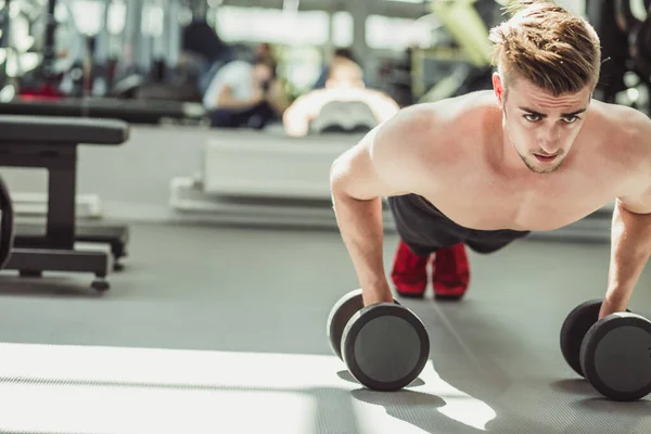 Jonge bodybuilder push-up kracht pushup oefening met halter in een fitness workout — Stockfoto