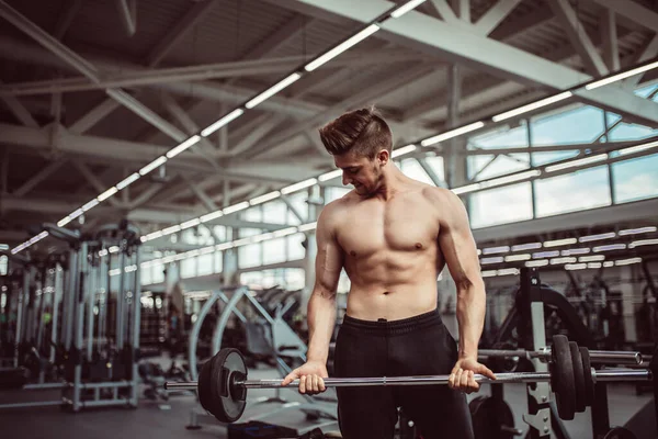 Ung man böjande muskler med skivstång i gymmet — Stockfoto