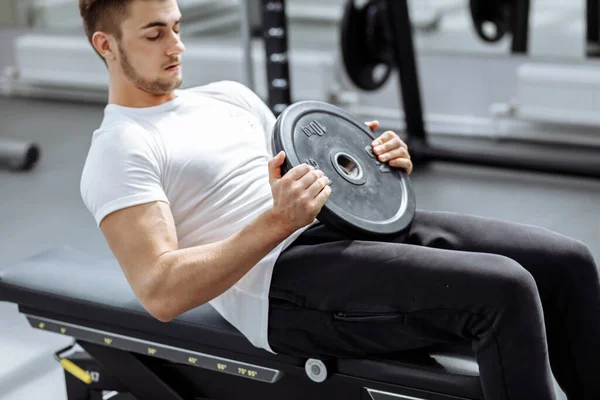 Muskularny facet ćwiczący mięśnie brzucha w nowoczesnej siłowni. Fit man robi chrupki na siłowni.. — Zdjęcie stockowe