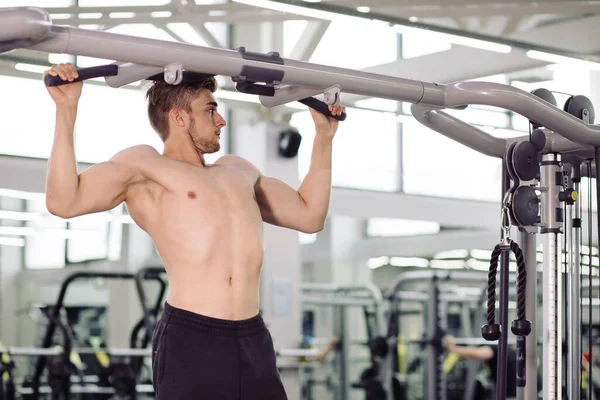 Bodybuilder performing exercise with gym training mashine — Stock Photo, Image