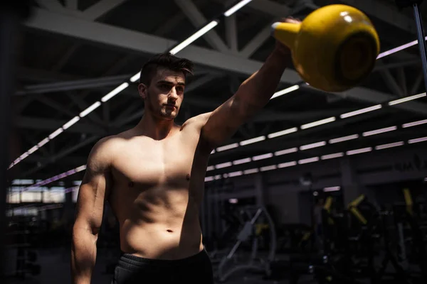 Young fitness man is training by kettlebell.