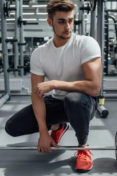Attraktiver Bodybuilder drinnen in gut ausgestattetem Fitnessstudio, bereiten Sie sich darauf vor, Gewicht zu heben — Stockfoto