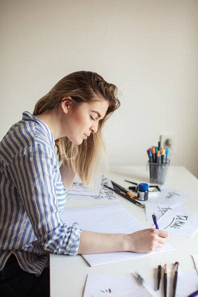 Woman make calligraphy writings, make art on paper using sign pen brush