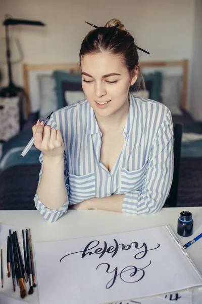 Jovem bela senhora sentado na mesa branca e pensar em caligrafia — Fotografia de Stock