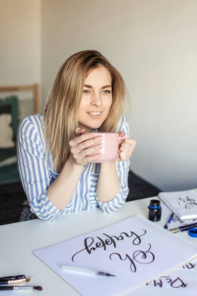 Zamknij się kobieta pisanie piękne notatki na papierze na białym biurku podczas picia kawy lub herbaty — Zdjęcie stockowe