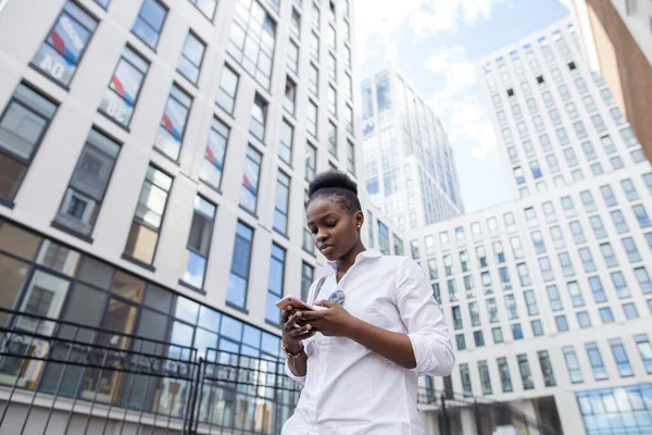 Afroamerikanerin mit Rucksack geht draußen spazieren und telefoniert — Stockfoto