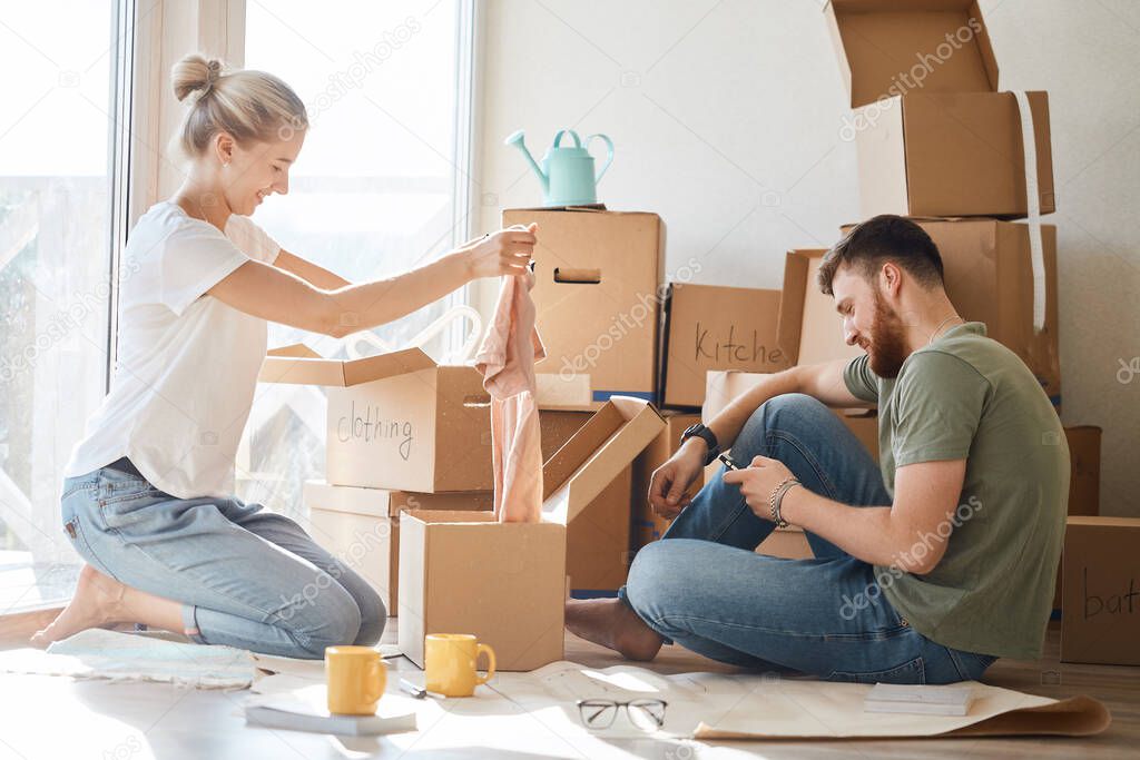 couple in new apartment unpacking cardboard boxes