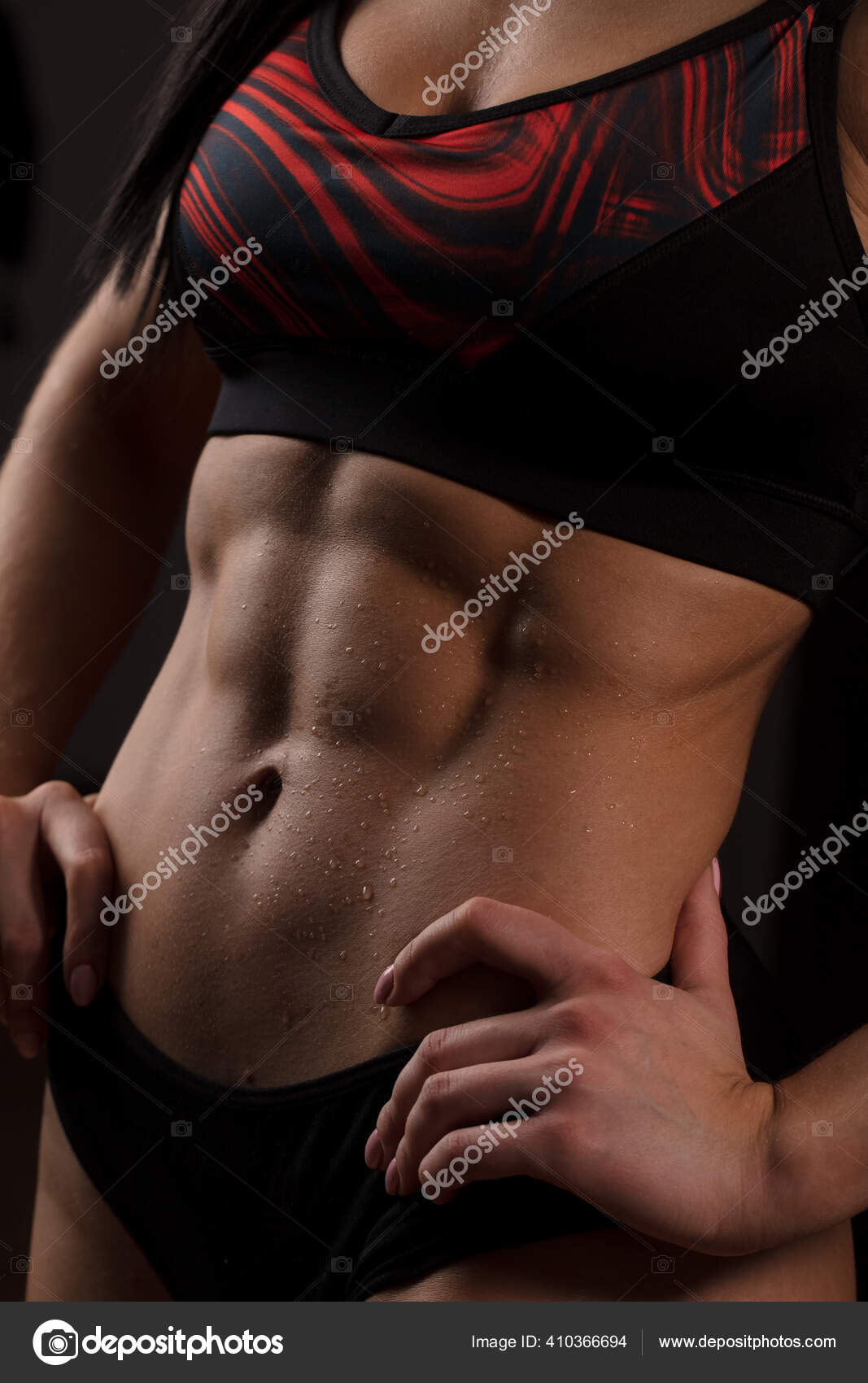 Unrecognizable woman showing off her perfect muscular ripped abs, close up.  Stock Photo by ©ufabizphoto 410366694