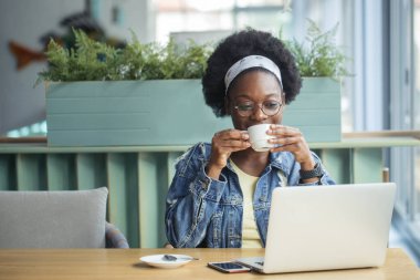 Afrikalı kadın blogcu, bir kafede öğle yemeği sırasında yeni bir yazı yazıyor..