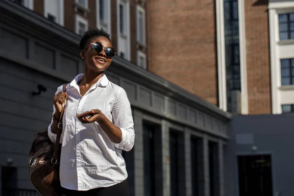 Africano mulher americana com mochila andando ao ar livre e falando no telefone móvel — Fotografia de Stock