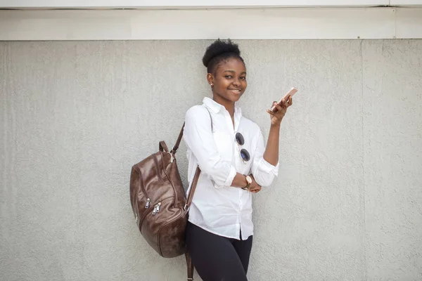 Beautiful african american woman in the street against the white wall. — Stock Photo, Image