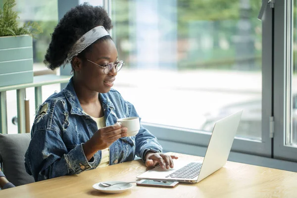 African female blogger, typing a new post during lunchtime at a cafe.