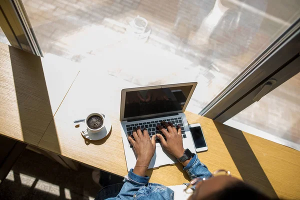 Manhã de trabalho de mulher de negócios Africano com um laptop e café, vista superior. — Fotografia de Stock