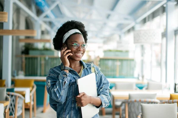 Hipster tmavé pleti žena s africkým účesem mluví na chytrý telefon v kavárně. — Stock fotografie