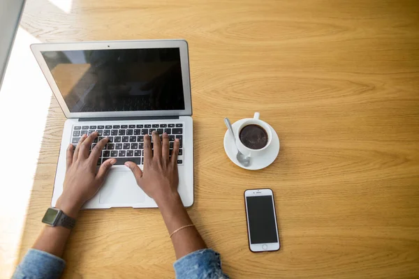 Manhã de trabalho de mulher de negócios Africano com um laptop e café, vista superior. — Fotografia de Stock