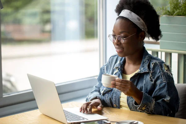 Blogger africana, escribiendo un nuevo post durante la hora del almuerzo en un café. — Foto de Stock