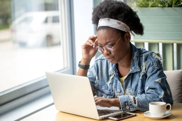 Blogger africana, escribiendo un nuevo post durante la hora del almuerzo en un café. — Foto de Stock