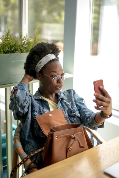 Mujer afroamericana con el pelo oscuro muy rizado, haciendo selfie, sonriendo a la cámara —  Fotos de Stock