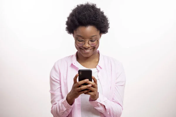 Sorrindo menina africana alegre mensagens de texto uma mensagem engraçada para um amigo — Fotografia de Stock