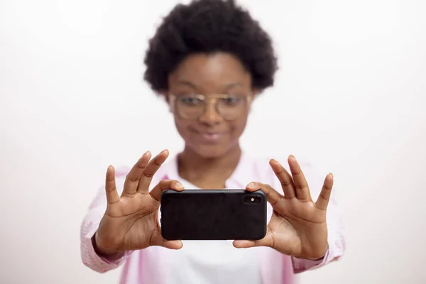 Bonita mulher de raça mista verificando a câmera de um novo telefone inteligente — Fotografia de Stock