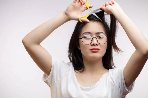 Menina asiática perturbada com problemas com cabelos longos, corte pontas duplas com tesoura — Fotografia de Stock