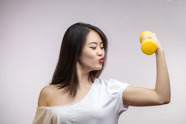 Mujer asiática con mancuernas, muestra su fuerza, bíceps de entrenamiento, aislado. — Foto de Stock