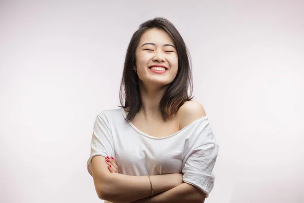 Młoda szczęśliwa Azjatka uśmiecha się i czuje się szczęśliwa, pozując samotnie nad białą ścianą — Zdjęcie stockowe