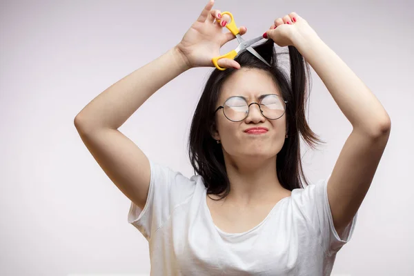 Verärgerte asiatische Mädchen haben Probleme mit langen Haaren, schneiden Spliss mit der Schere — Stockfoto