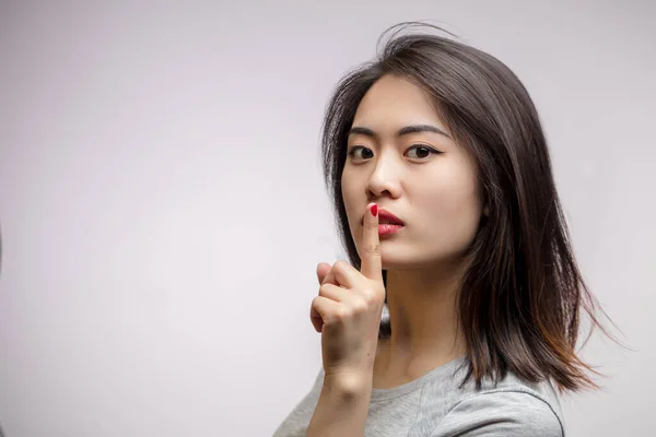 Asian female model demand silence, isolated over white background