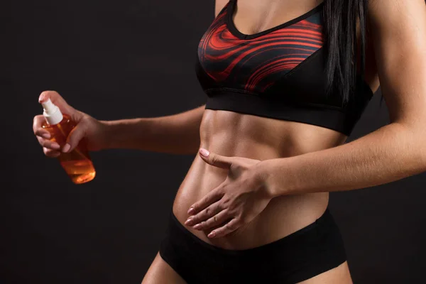 Bodybuilderin hüllt sich vor schwarzem Hintergrund in Öl. — Stockfoto