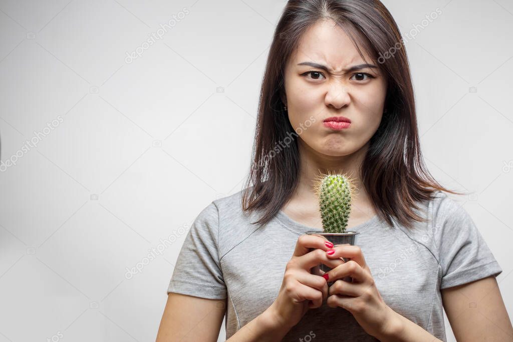 Unhappy Asian woman with a small cactus. Hair ans Skin, Care and Problems.