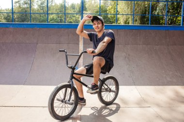 Sürücü kaykay parkında BMX 'te oturuyor.