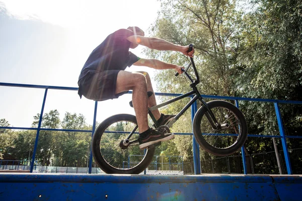 Uomo va in bicicletta sulla ruota posteriore della BMX. maschio pilota fa trucchi su BMX bici — Foto Stock