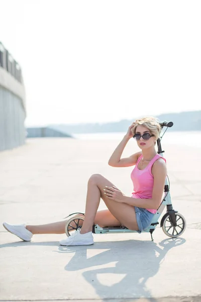 Positiv blond kvinna sitter på blå sparkcykel — Stockfoto